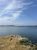 Little Deer Isle coast at Acadia National Park with rocky promontory, golden coastal grass, and calm blue water under a clear sky.