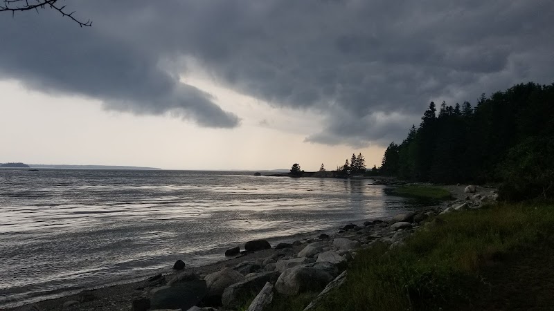 Little Deer Isle shoreline along Acadia National Park with rocky coast and dark stormy clouds overhead.