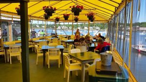 Lobster Pound dining deck under a yellow canopy at Acadia National Park, overlooking a harbor with boats.