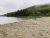 Echo Lake Beach along the sandy shore at Acadia National Park, with forested hills and a cloudy sky.