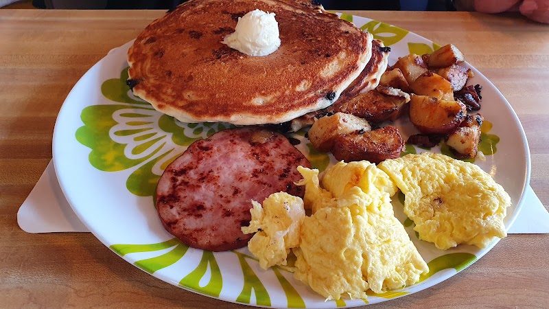 Plate at Acadia National Park with pancakes and butter, scrambled eggs, ham, roasted potatoes, and sausage.