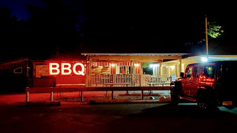 Nighttime at Acadia National Park shows a wooden BBQ eatery with red neon sign and a parked red pickup.