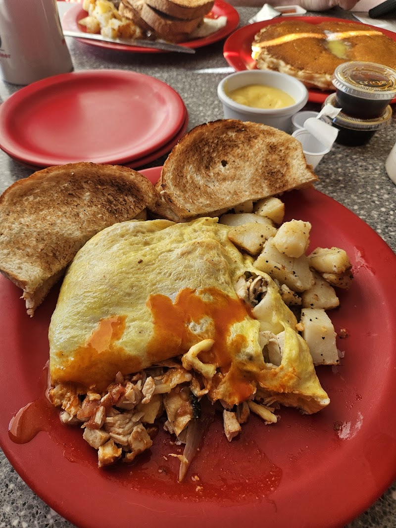 Omelette breakfast with potatoes and toast on a red plate in Acadia National Park, near a casual diner setting.