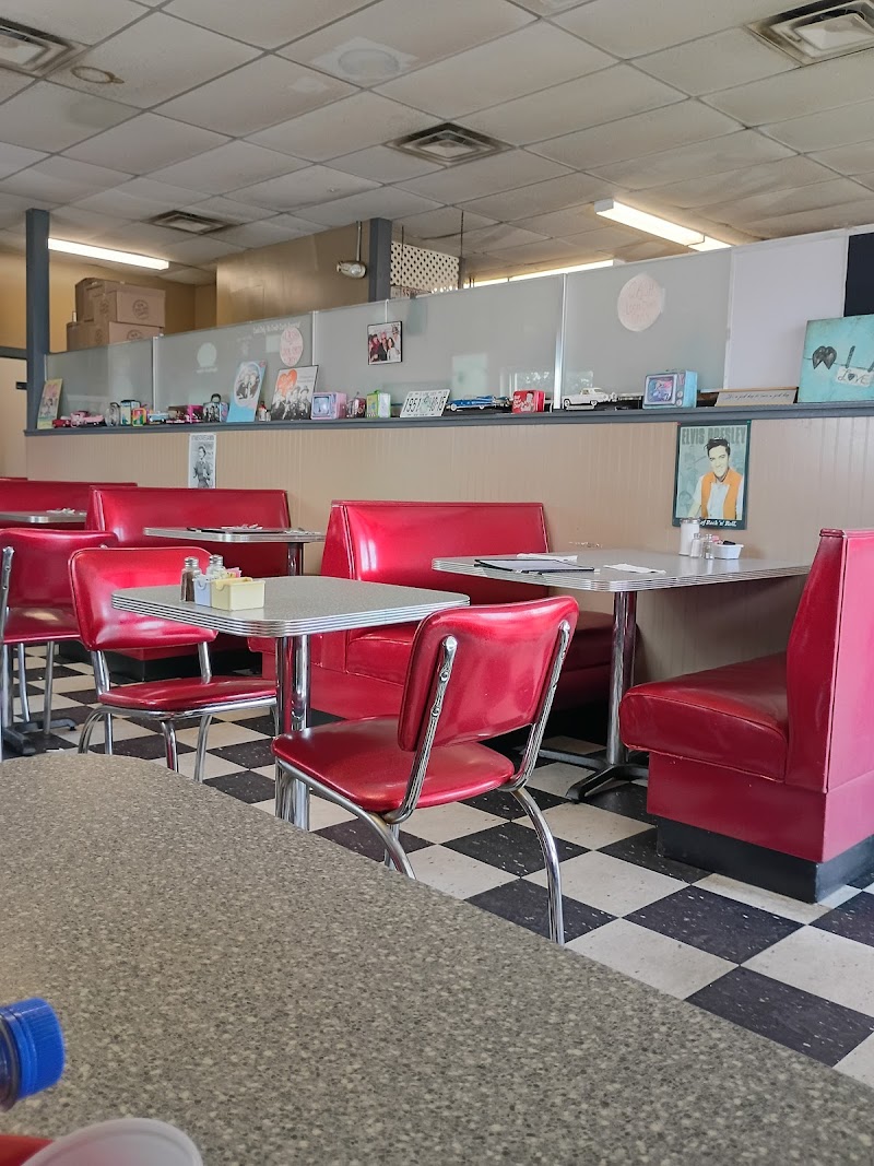 Interior of a retro red-booth diner in Acadia National Park, with a checkered black-and-white floor and vintage decor.