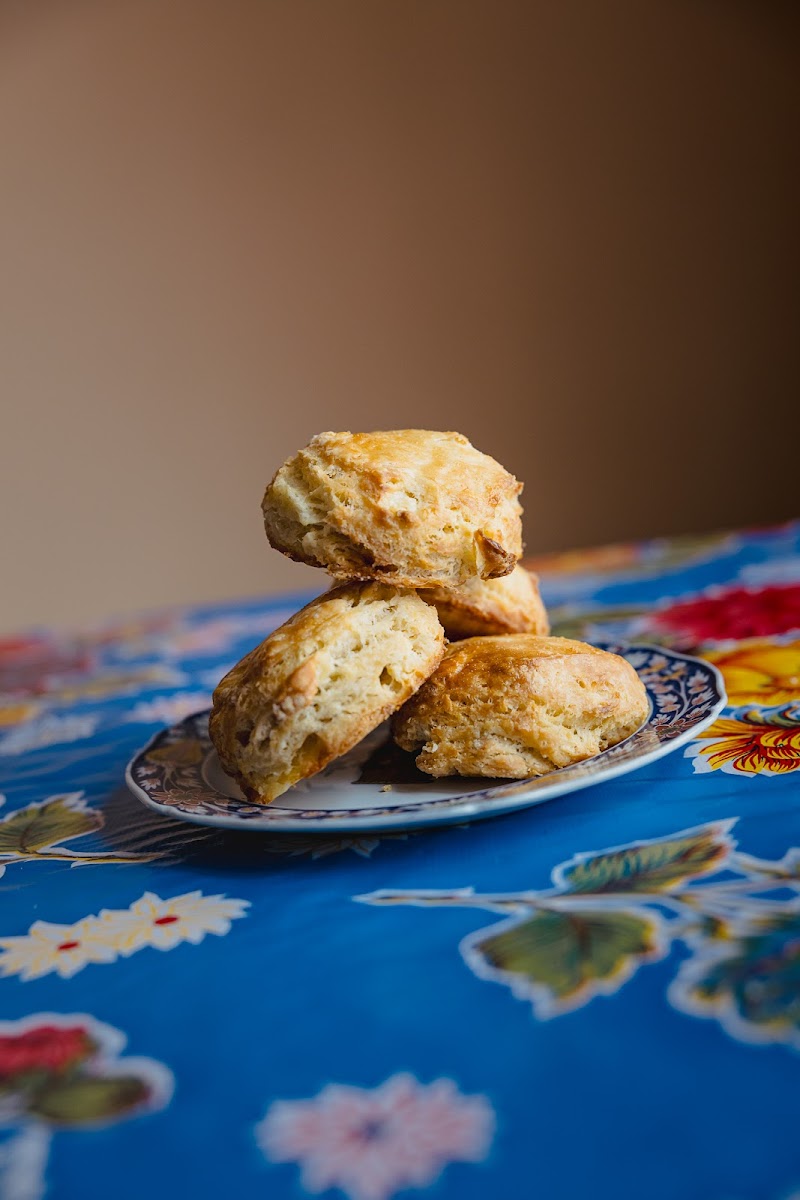 Stack of golden-brown scones on a decorative plate atop a bright blue floral tablecloth in Acadia National Park.