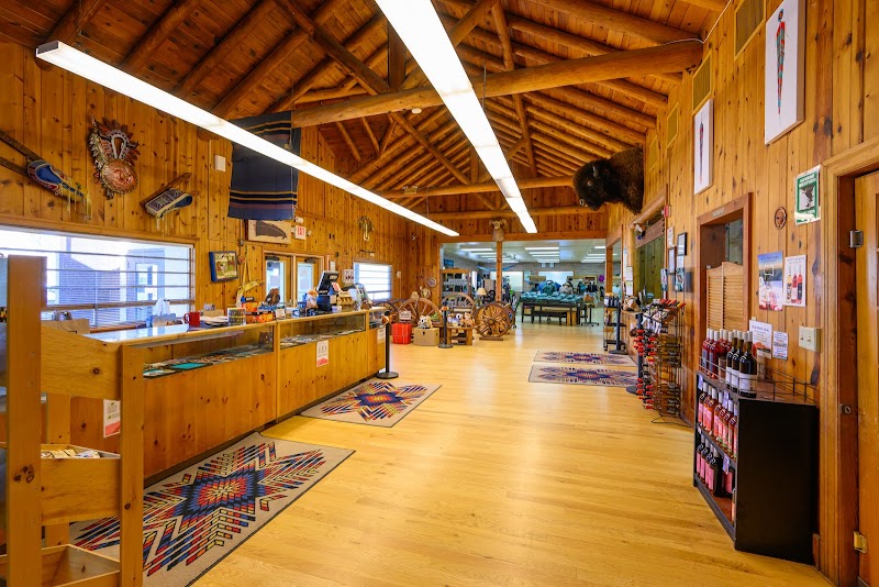 Inside a warm wooden gift shop at Badlands National Park, a long checkout counter, colorful woven rugs, and shelves with souvenirs.