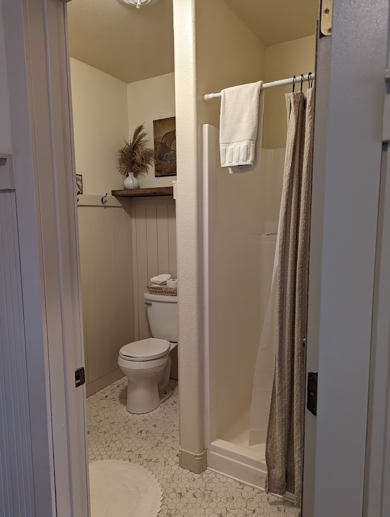 Cozy bathroom with a glass-free shower, gray patterned curtain, toilet, towel rack, and a small shelf with decor in Badlands National Park