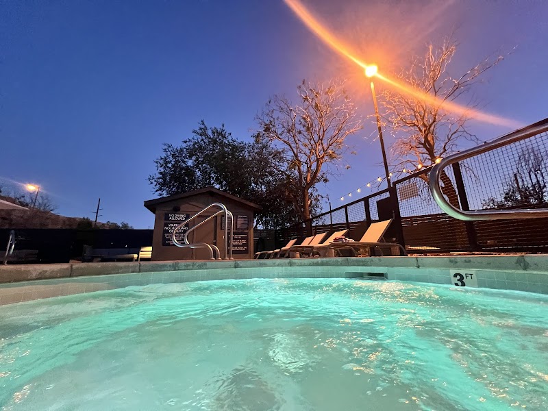 Evening pool scene at Arches National Park lodging, turquoise water, lounge chairs, metal railings, and a small pool hut.