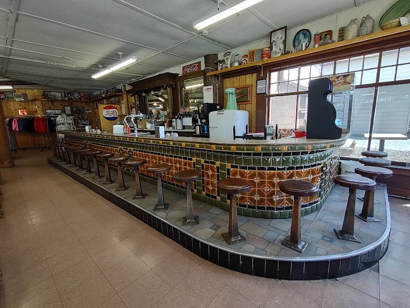 Inside Yellowstone National Park, a retro curved tiled counter with wooden stools, coffee station, and vintage shop decor.