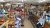 Inside a rustic Yellowstone National Park gift shop, shelves brim with snacks and souvenirs, while a girl in a striped shirt sits near a long counter.