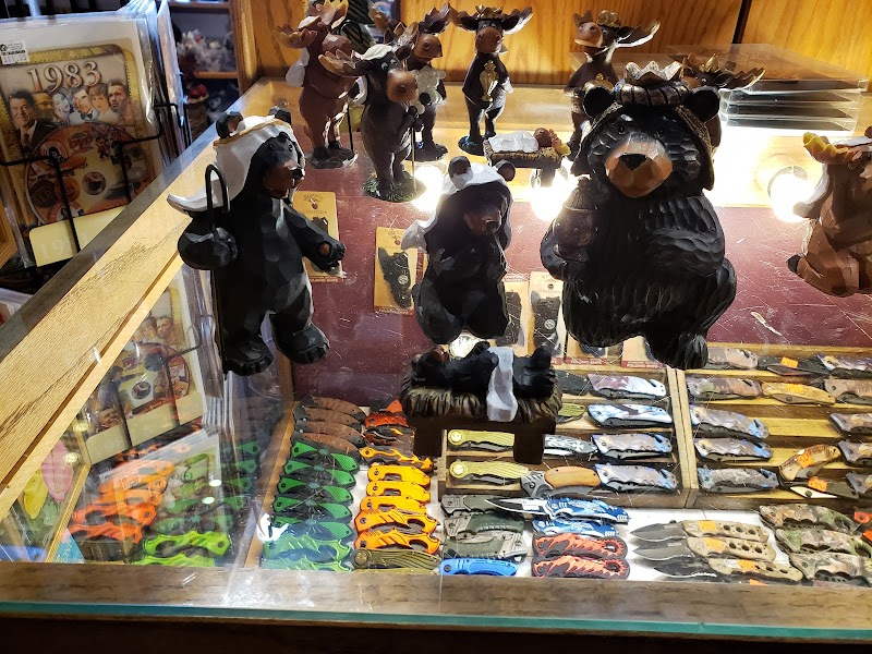 Colorful souvenir knives and wooden bear figurines displayed in a glass case at a Yellowstone National Park gift shop.