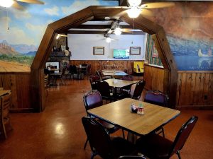 Interior view of the Terlingua Ranch Lodge dining area in Big Bend National Park, featuring a wooden arch, mural walls, and casual tables.