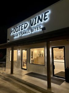 Nighttime storefront of a restaurant in Arches National Park with a bright, curved sign and warm interior lighting.