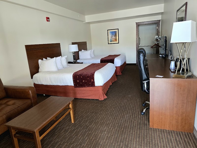 Spacious hotel room in Yellowstone National Park with two queen beds, desk, sofa, and warm decor.