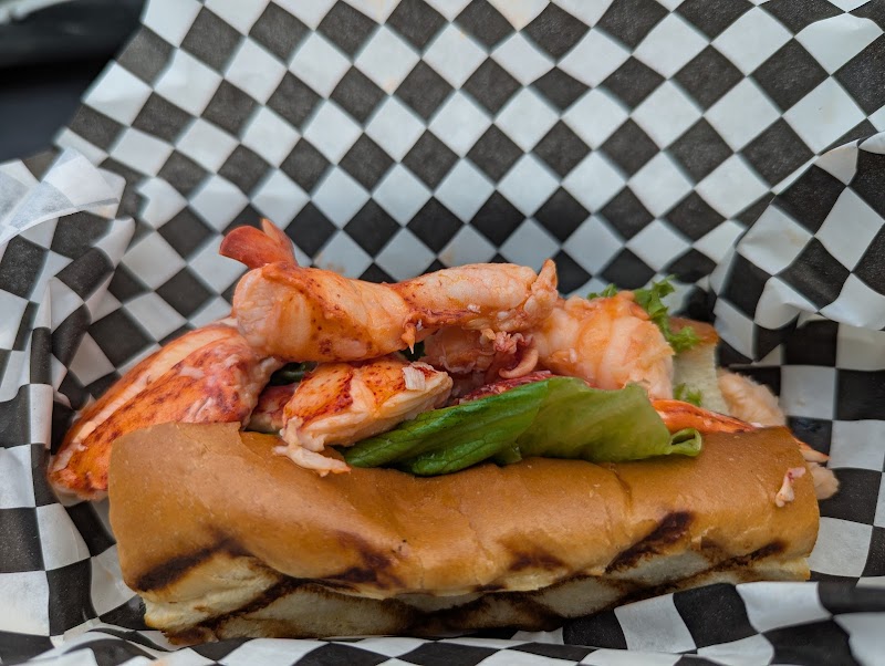 Lobster roll with lettuce on a toasted bun, wrapped in checkered paper at Acadia National Park.