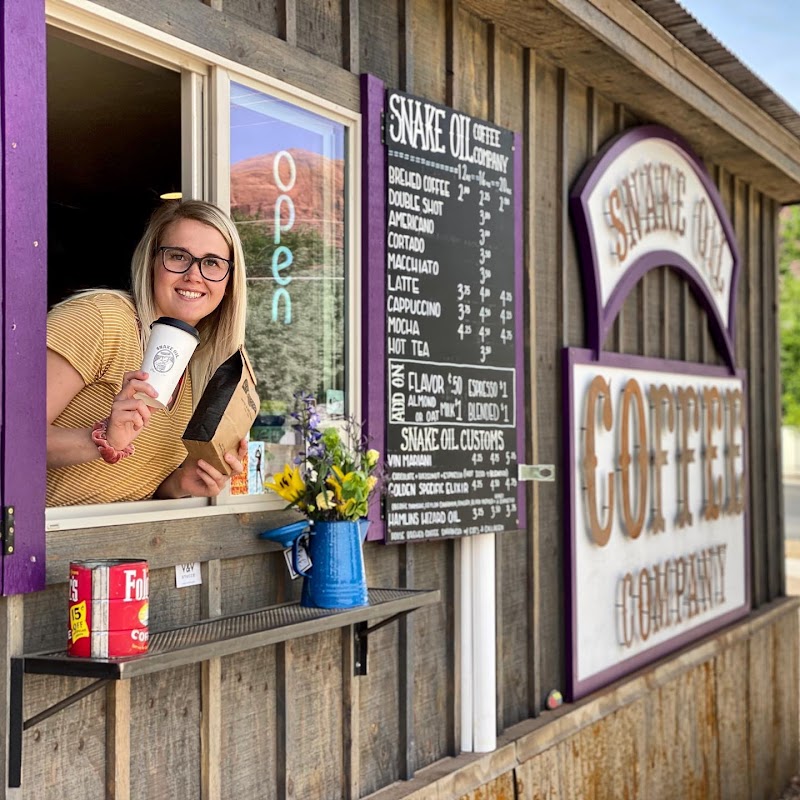 Smiling barista leans from a rustic shack window, holding a cup beside a chalkboard menu at Arches National Park.
