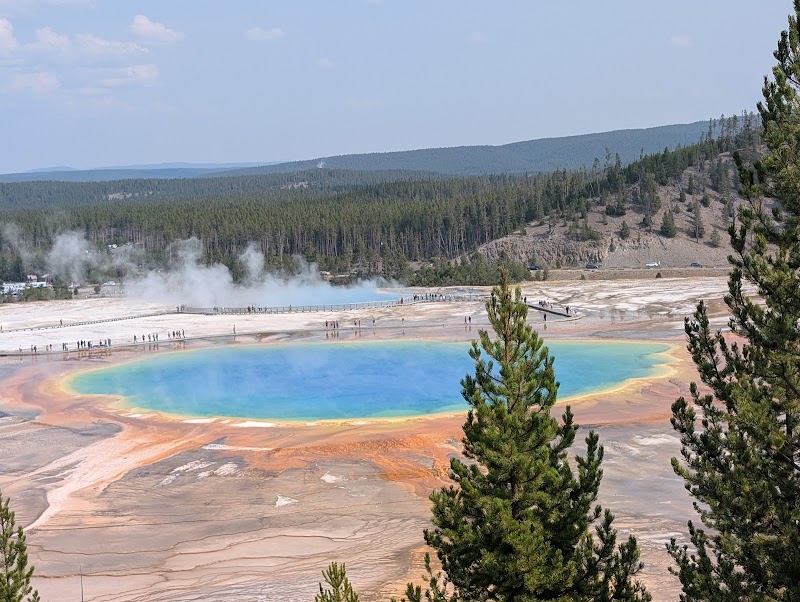 Prismatic hot spring in Yellowstone National Park with vivid blue center, orange ring, steam, and boardwalks.