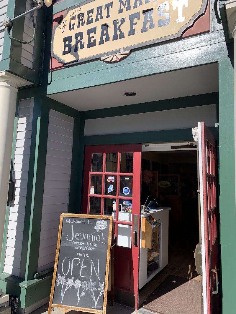 Cozy cafe entrance with red-framed doors, chalkboard OPEN sign, and a weathered storefront in Acadia National Park.