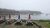 Picnic tables with red and blue umbrellas overlooking a foggy harbor with boats in Acadia National Park.