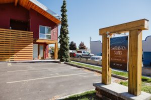 Lodge-style building with a wooden-frame sign near a Glacier National Park parking lot.