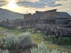Old Trail Town at Yellowstone National Park features historic wooden storefronts and moored wagons along a dusty street.