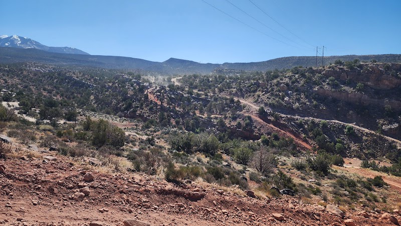 Wide view over a red desert valley with rocky hills and a winding dirt road in Arches National Park.