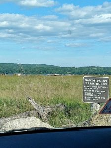 Sandy Point at Acadia National Park with open grassy marsh and a park rules sign in view.