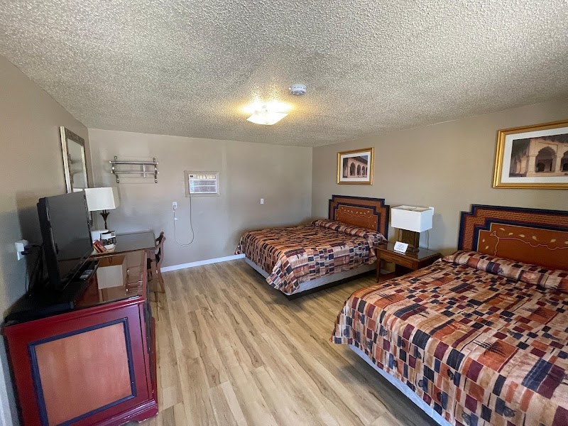 Guest room in Badlands National Park with two double beds, patchwork quilts, bedside lamps, framed art, and wood flooring.