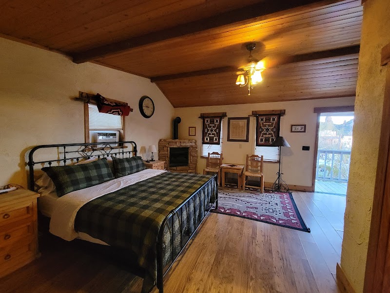 Ten Bits Ranch bedroom in Big Bend National Park with a wrought-iron bed, plaid bedding, and a stone fireplace.