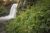 Moose Falls in Yellowstone National Park cascades beside rugged rocks and lush alpine vegetation.