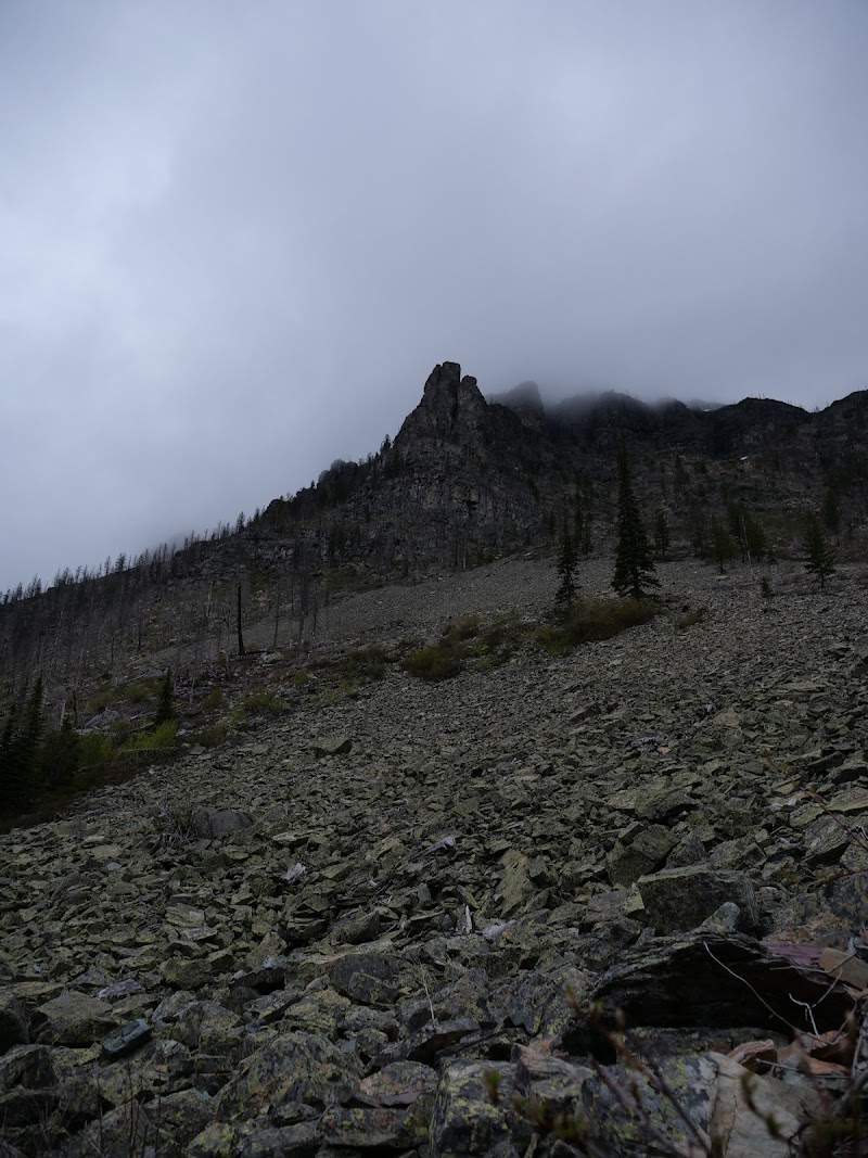 Snyder Lake Campground area in Glacier National Park framed by rocky talus and a clouded ridge.