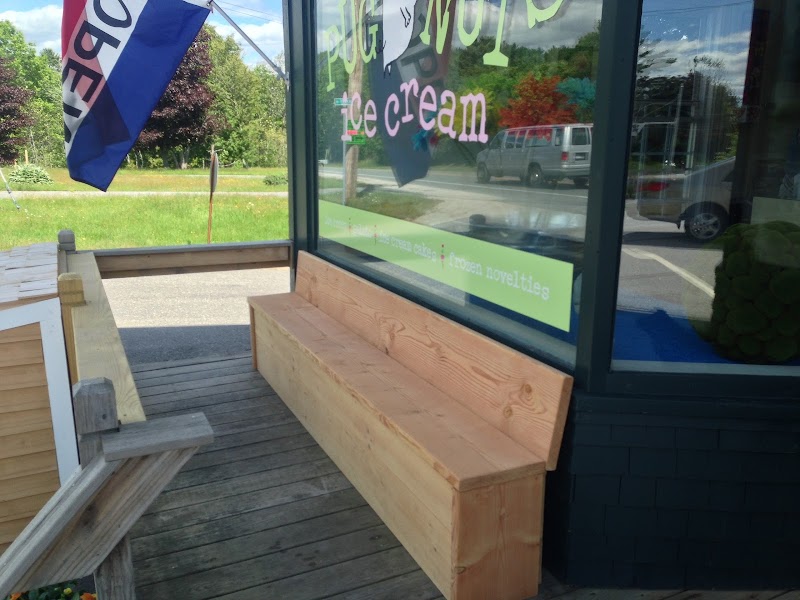 A wooden bench sits outside a bright ice cream shop window along a park road in Acadia National Park.