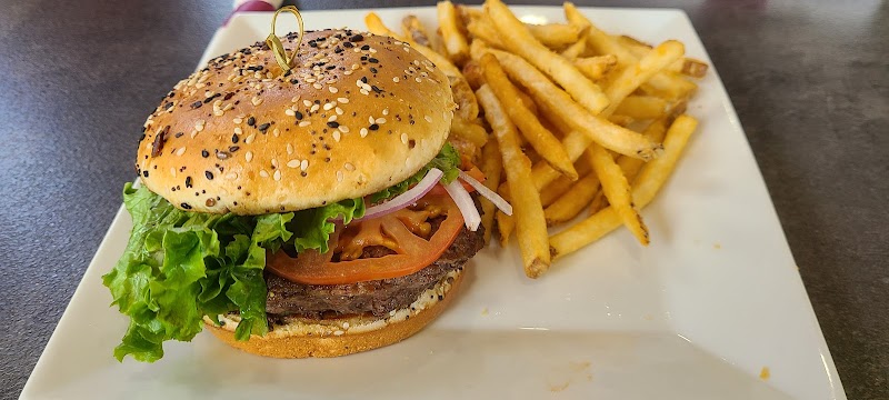 Juicy hamburger with lettuce, tomato, and onions on a sesame bun served with fries in Acadia National Park.