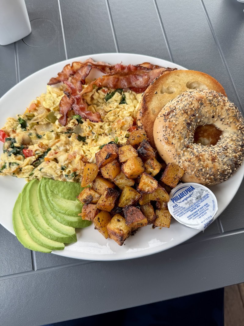 Hearty breakfast plate at Acadia National Park featuring scrambled eggs, crispy bacon, potatoes, avocado slices, and a bagel.