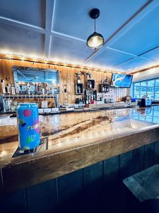 Warm-lit bar interior with a wooden counter inside Acadia National Park area.