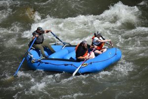 Three paddlers navigate whitewater on the Yellowstone River in Yellowstone National Park during a guided rafting trip.