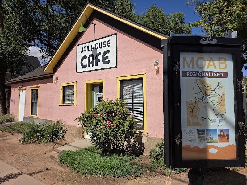 Pink café with yellow trim, rose bush, and a MOAB regional info display nearby in Arches National Park.
