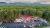 Aerial view of a red-roofed restaurant amid tall pines, a busy parking lot, and dense forest at Acadia National Park.