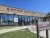 Brown brick visitor center with large glass windows and double doors, and a hours sign at Badlands National Park.
