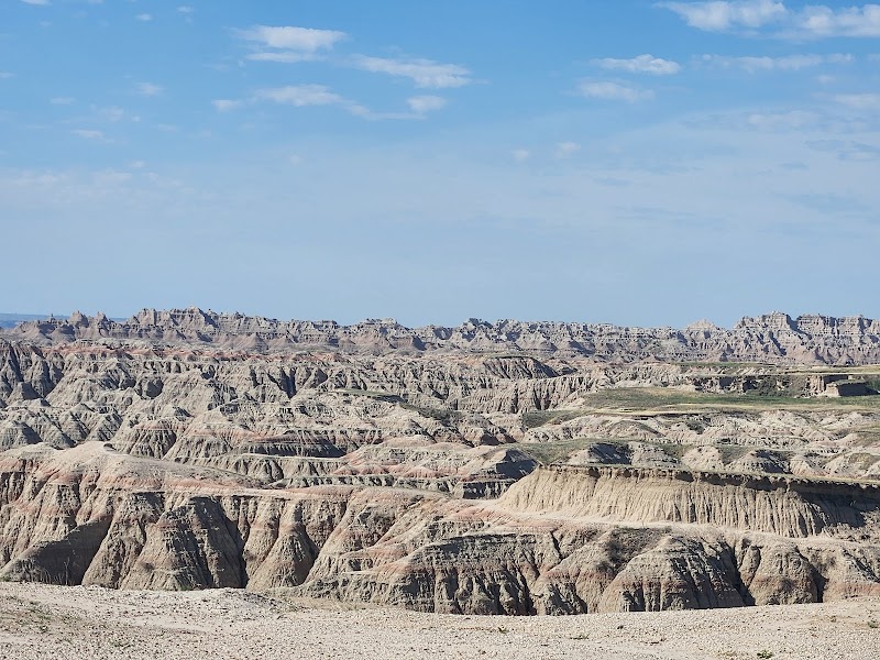 Rugged eroded badlands formations stretch into the distance under a blue sky in Badlands National Park.
