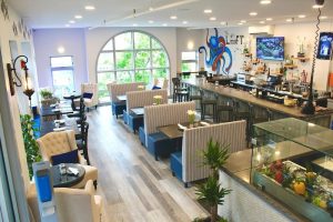 Cozy dining room inside a seafood restaurant in Acadia National Park, featuring striped booths, a curved window, and a blue octopus mural.