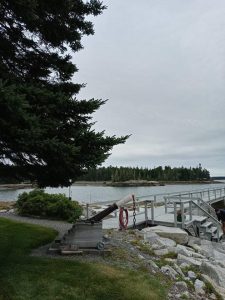 Brooklin waterfront cannon at a rocky shoreline with a wooden pier along Acadia National Park coastline.