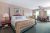 Luxurious Bar Harbor hotel room with a king bed, elegant bedding, and warm decor in Acadia National Park.