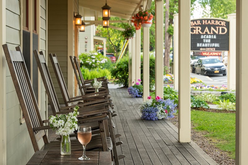 Porch lined with rocking chairs and flower baskets at a lodging in Bar Harbor, Acadia National Park.
