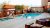 Pool area with a rectangular pool, hot tub, lounge chairs, and shaded pergolas beside a lodge at Arches National Park.