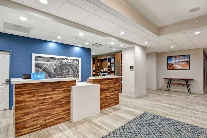 Lobby reception with a wooden front desk, blue wall, bookshelves, and a landscape photo in Arches National Park.