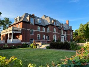 Historic brick building in Acadia National Park with a white porch and well-kept lawn.
