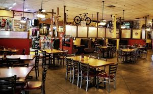 Inside a casual dining hall with wooden tables and metal chairs, bikes hung from the ceiling in Arches National Park.