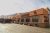 Adobe-style restaurant with large windows and potted plants along a sunlit parking lot in Arches National Park.