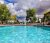 Clear blue swimming pool at a campground near Arches National Park, with parked RVs behind a black fence and green trees under a cloudy sky.